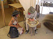 A man seated on a stool handles fossils while a woman kneeling nearby looks on.