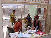 Two costumed burners work the Earth Guardian information desk as two more play guitars behind them.