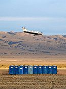 A small plane descends behind a row of portable toilets.